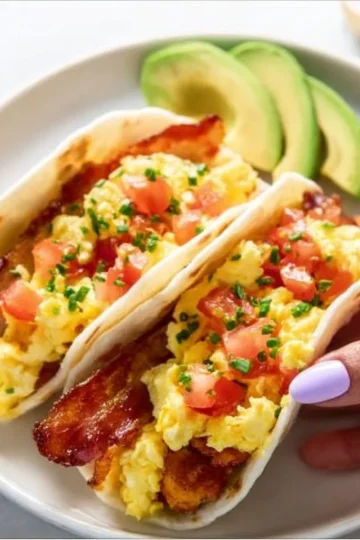A plate of colorful breakfast tacos filled with eggs and vegetables