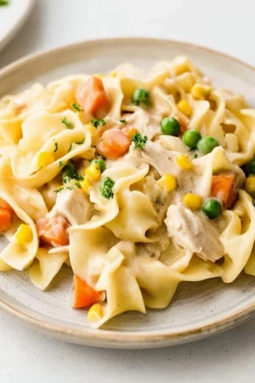 Delicious Chicken Noodle Casserole served in a baking dish with herbs on top.