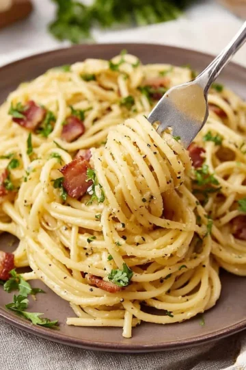 Plate of easy spaghetti carbonara topped with cheese and parsley