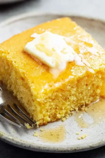 Delicious super moist cornbread served in a rustic setting with butter on top.