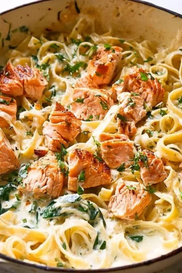 Creamy salmon pasta dish topped with mixed greens