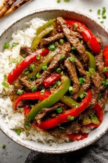 Delicious Crockpot Pepper Steak served with fresh vegetables and rice