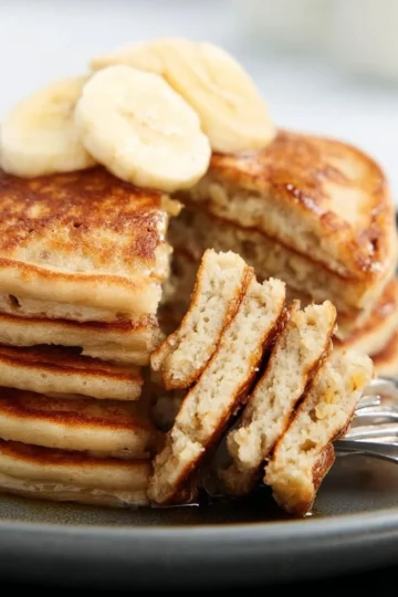 Fluffy homemade banana pancakes served with fresh fruit and syrup.