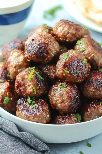 Delicious Greek meatballs served with tzatziki sauce and fresh herbs.