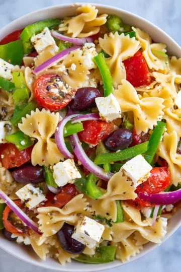 Bowl of vibrant Greek Pasta Salad with olives, feta, and fresh vegetables
