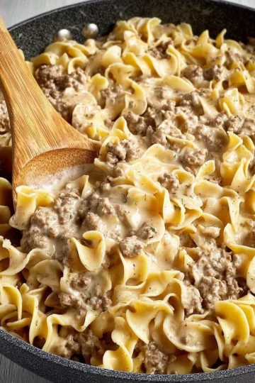 Delicious Ground Beef Stroganoff served with pasta and garnished with parsley.
