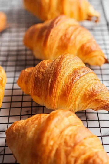 Homemade croissants fresh out of the oven showing flaky layers and golden color.