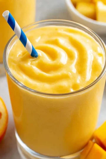 Delicious mango smoothie in a glass topped with mint leaves