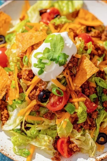Delicious taco salad topped with Doritos and fresh ingredients.