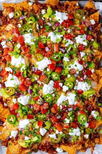 Plate of colorful vegetarian nachos with cheese, tomatoes, and jalapeños