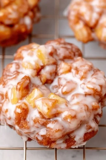 Homemade apple fritters dusted with powdered sugar on a plate