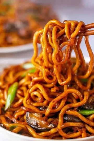 A plate of grilled udon noodles served with vegetables and tasty sauce.