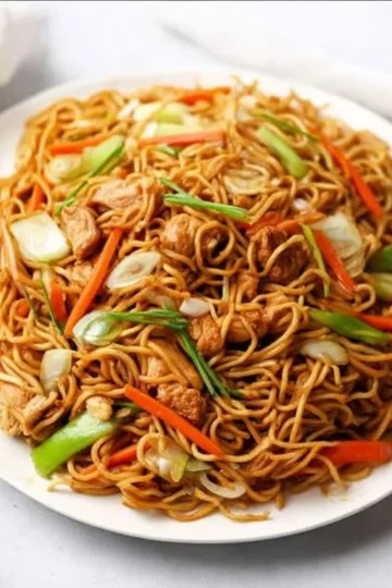 A bowl of quick and easy chicken chow mein topped with vegetables