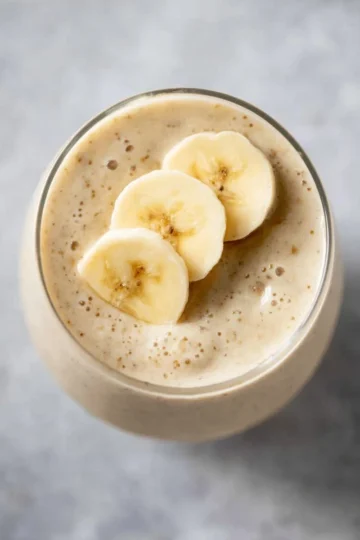 Delicious homemade banana smoothie in a glass with fresh bananas